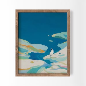 Puede incluir: Una impresión artística enmarcada representa a un astronauta sentado en un paisaje colorido en forma de nube bajo un cielo azul profundo. La obra de arte utiliza azules, verdes y naranjas, creando una escena serena e imaginativa. El marco es de madera.