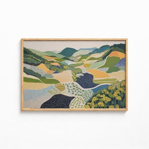 May include: A rectangular landscape painting in a light wood frame depicting rolling hills and fields. The artwork features a patchwork of green, yellow, blue, and dark navy patterns, including dots, stripes, and solid blocks, representing a textured countryside.