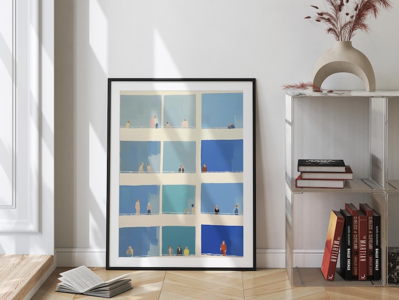 a framed collage of blue squares with various people in different poses, placed on a wooden floor next to a bookshelf.