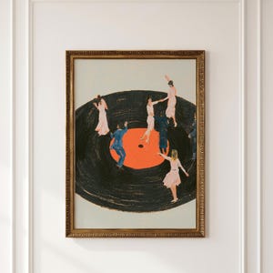 May include: A framed wall art print featuring a large black vinyl record with a bright orange center label. Several figures in light pink dresses and blue suits are depicted dancing on the surface of the record against a light gray background.
