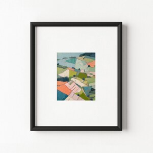 May include: A framed art print featuring an abstract landscape painting with geometric shapes in shades of orange, green, blue, and cream. The artwork is centred within a white mat and enclosed in a simple, thin black rectangular frame.