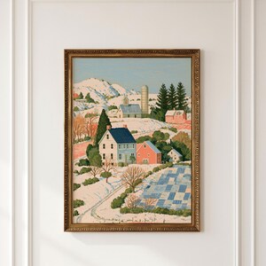 Könnte beinhalten: Ein gerahmtes Landschaftsgemälde, das eine verschneite ländliche Szene mit einem Haus mit blauem Dach, einer roten Scheune und einem hohen Silo zeigt. Das Kunstwerk zeigt schneebedeckte Hügel, verstreute Nadelbäume und ein blau-weiß kariertes Feld.