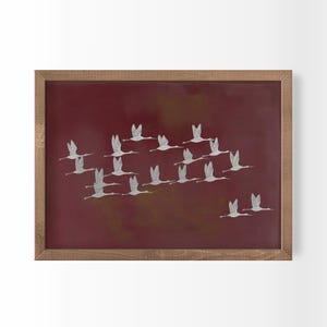 May include: A rectangular wall art piece featuring a deep maroon background with a flock of white birds in flight. The artwork is enclosed in a light brown wooden frame, showcasing a repeating pattern of birds moving across the dark surface.