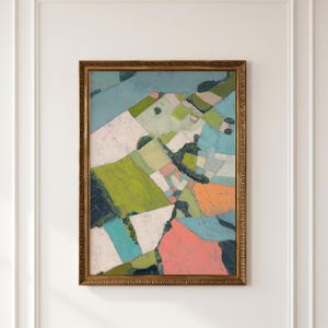 May include: A framed painting depicting an aerial view of a landscape with geometric fields in shades of green, blue, white, orange, and pink. The artwork is enclosed in an ornate, textured gold-colored frame with a repeating decorative pattern.