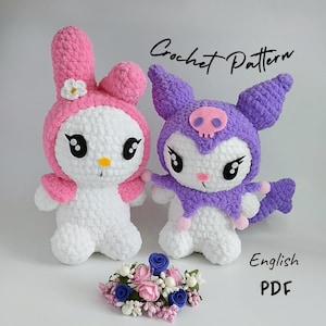 May include: Crochet pattern for two plush toys, one pink and white with bunny ears and a flower, and one purple and white with bat ears and a skull. The pattern is available in English PDF format.