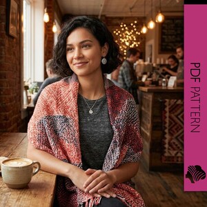 Peut inclure: Une femme porte un châle à motifs rouges, oranges et bleus, un t-shirt gris et un collier argenté. Elle est assise à une table en bois avec une tasse de café et une pâtisserie. L'arrière-plan comprend un mur de briques et un café.