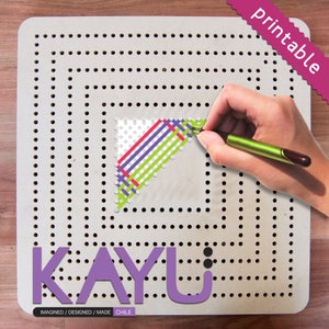 May include: A printable pegboard with a colorful geometric design. The design is made up of green, purple, and red lines on a white background. The pegboard is labeled "KAYU" and "IMAGINED / DESIGNED / MADE CHILE".