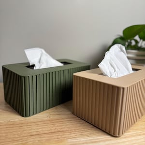 Peut inclure: Deux boîtes à mouchoirs, l'une verte et l'autre marron, avec une texture nervurée. Les deux boîtes contiennent des mouchoirs blancs.