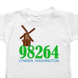 May include: White t-shirt with a brown windmill graphic and green text that reads "98264 LYNDEN, WASHINGTON".