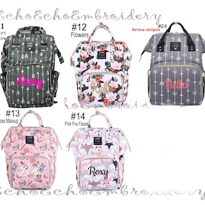 May include: Ten different diaper bags with various patterns and colors. The bags have a zippered front pocket and a large main compartment. The bags are personalized with names like Avery, Bella, Kyle, and Roxy. The bags are numbered 11 through 14 and 24.