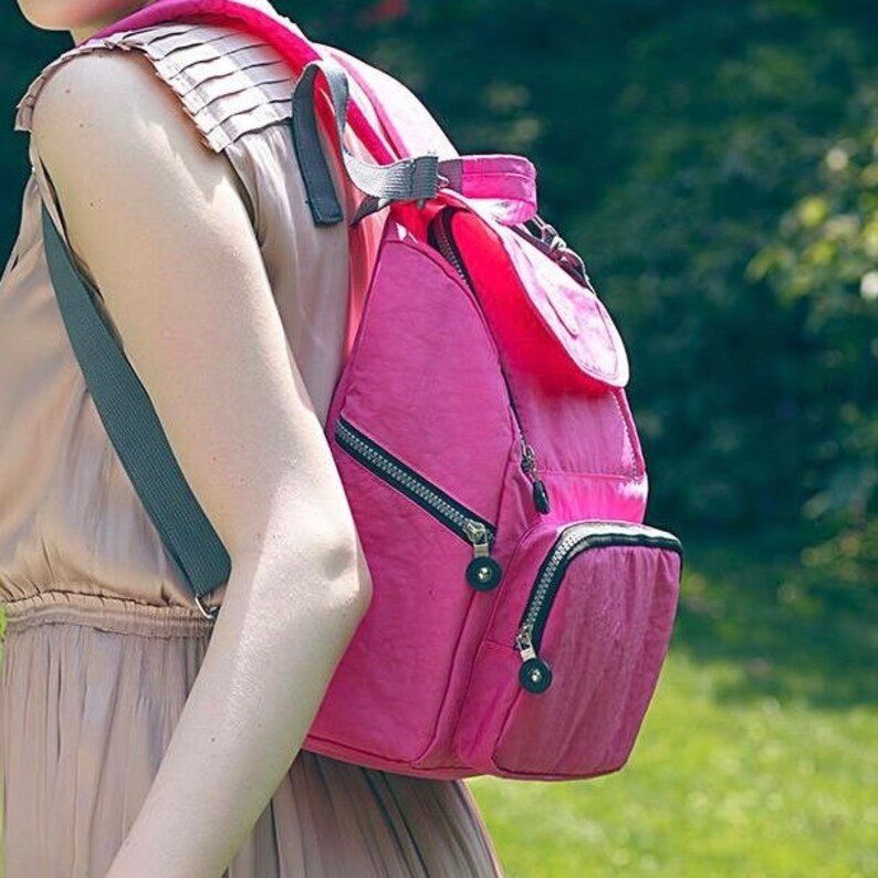 May include: A pink nylon backpack with multiple zippered compartments and adjustable straps.