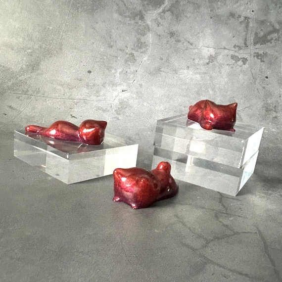 A handmade resin cat sculpture that doubles as a multi-tool rest — the 'phoenix glow' colorwork in red and purple makes it genuinely striking on a desk.