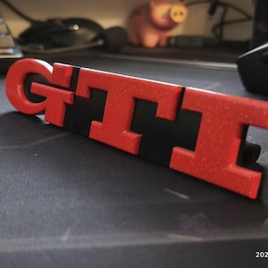 May include: A white ceramic mug with a black handle and the text "But First, Coffee" in a bold, black font. The mug is set against a neutral background, highlighting its simple design.