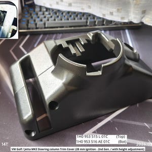 Könnte beinhalten: Eine dunkelgraue Lenksäulenverkleidung für einen VW Golf oder Jetta MK3. Die Kunststoffabdeckung hat ein gebogenes Design mit mehreren Öffnungen und Befestigungspunkten. Der Text auf dem Bild weist auf eine 28-mm-Zündung und Höhenverstellung hin.