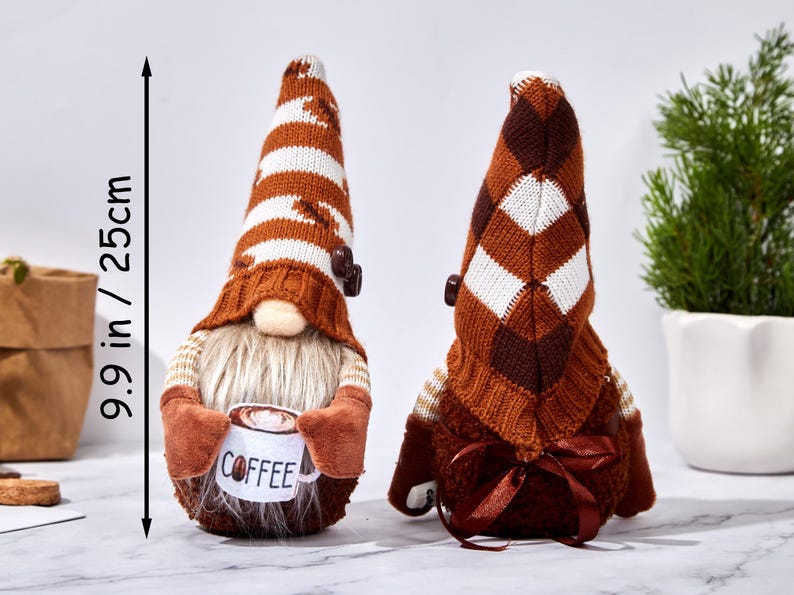May include: Two decorative gnomes, each approximately 9.9 inches (25 cm) tall. One gnome holds a coffee cup. They have brown and white striped hats, beige beards, and brown mittens. The gnomes are a charming addition to home decor.