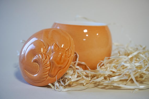 A beautifully glazed orange ceramic pet urn with personalization — a genuinely thoughtful, emotionally resonant keepsake for grieving pet owners that you'd never find at a big-box store.
