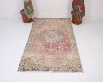 Puede incluir: Alfombra rectangular de aspecto envejecido, con un diseño central de medallón. La paleta de colores incluye rojo descolorido, beige y azul marino. La alfombra está colocada sobre una superficie blanca. Medidas en centímetros.