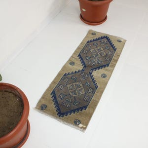 May include: A beige runner rug with a blue and brown geometric pattern. The rug has a distressed look and is perfect for adding a touch of bohemian style to your home.