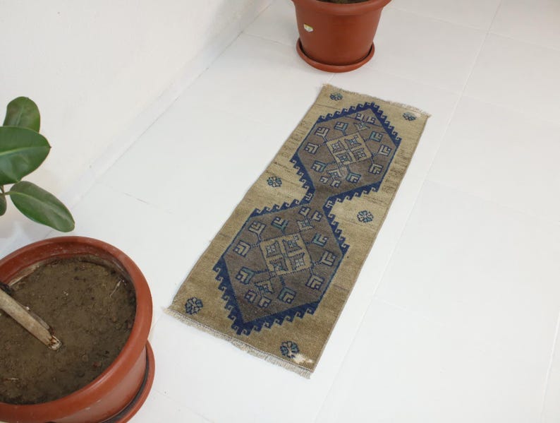 May include: A beige runner rug with a blue and brown geometric pattern. The rug has a distressed look and is perfect for adding a touch of bohemian style to your home.