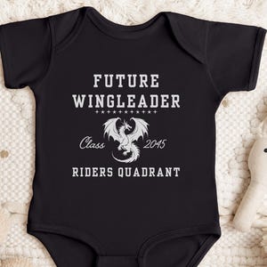 May include: Black baby onesie with white text that reads "Future Wingleader Class 2045 Riders Quadrant" and a white dragon graphic.