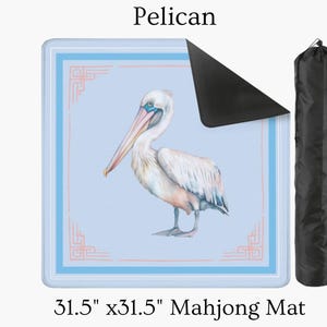 May include: A 31.5" x 31.5" Mahjong mat featuring a watercolor illustration of a pelican. The mat has a light blue background with a decorative border and a black carrying case. The word "Pelican" is at the top.