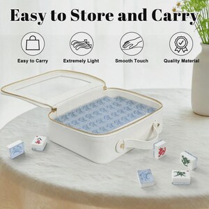 Puede incluir: Estuche blanco con cremallera y tapa transparente, que contiene fichas azules. El estuche tiene un asa y una cremallera dorada. Varias fichas de juego est&aacute;n esparcidas alrededor del estuche. El texto en la parte superior dice "Easy to Store and Carry".