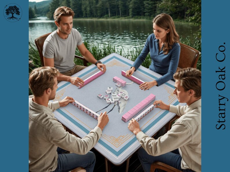 May include: A group of four people playing Mahjong around a square table. The table has a light blue surface with a decorative border. Pink Mahjong tiles and racks are visible. The game is set outdoors near a lake.