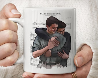 Może przedstawiać: Biały ceramiczny kubek z nadrukowaną ilustracją dwóch osób obejmujących się na tle zapisu nutowego. Tekst na górze brzmi I'LL BE THERE FOR YOU, Theme from FRIENDS oraz Music by Michael Skloff, Arranged by Dan Coates.
