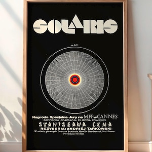 Könnte beinhalten: Gerahmtes Poster mit dem Titel "SOLARIS" in großen weißen Buchstaben auf schwarzem Hintergrund. Das Poster zeigt ein kreisförmiges Design mit roter Mitte und weißen Linien. Das Poster ist in einem Holzrahmen.