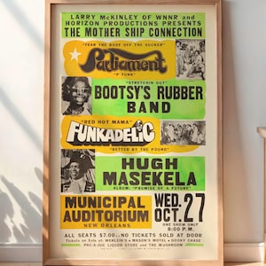May include: A framed vintage concert poster featuring Parliament, Bootsy's Rubber Band, Funkadelic, and Hugh Masekela. The poster is in a wooden frame and displayed indoors. The poster's text includes the date, location, and ticket information.