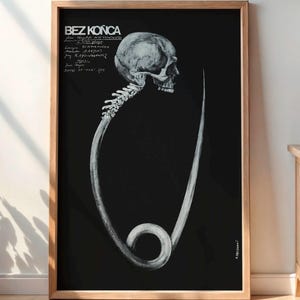 May include: A framed black and white poster with a skull and safety pin design. The poster has the text "BEZ KONCA" at the top. The artwork is displayed in a room with a wooden cabinet, a lamp, and a potted plant.