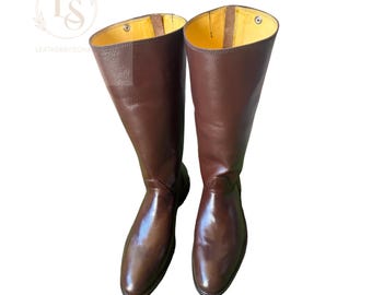 May include: A pair of brown leather riding boots with a yellow lining. The boots are tall and have a pointed toe.