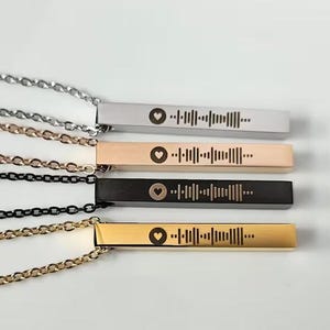 May include: Four silver bar necklaces with different coloured chains. Each bar has a heart and a unique barcode engraved on it.
