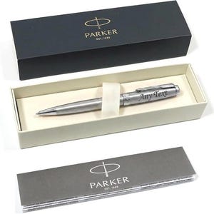 May include: A silver Parker pen with the text "Any Text" engraved on the barrel, presented in a black box with the Parker logo. The pen rests in a cream-colored interior, accompanied by a gray information card.