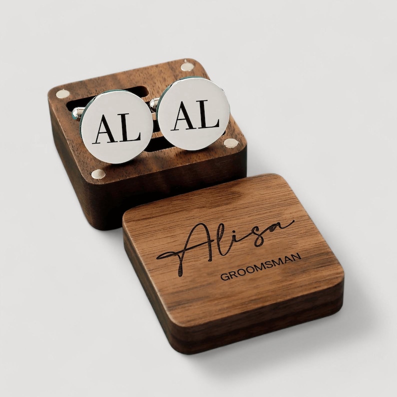 May include: A wooden box with a hinged lid, containing two silver cufflinks engraved with the initials "AL". The box is also engraved with the name "Alisa" and the word "Groomsman".