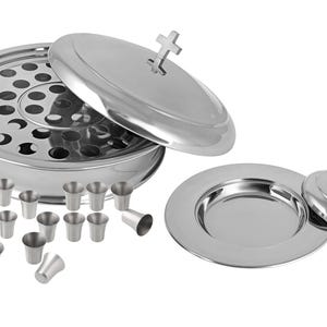 May include: A stainless steel communion set, including a bread holder with a lid, a serving plate with a lid, and small cups. The lids feature a cross-shaped handle. The set is designed for religious ceremonies.
