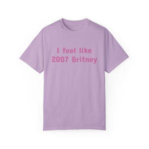 May include: A lavender t-shirt with the text "I feel like 2007 Britney" printed in pink.
