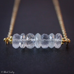 May include: A delicate gold chain necklace with a row of clear aquamarine gemstones.