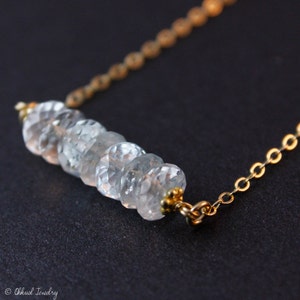 May include: A delicate gold chain necklace with a row of clear faceted gemstone beads.
