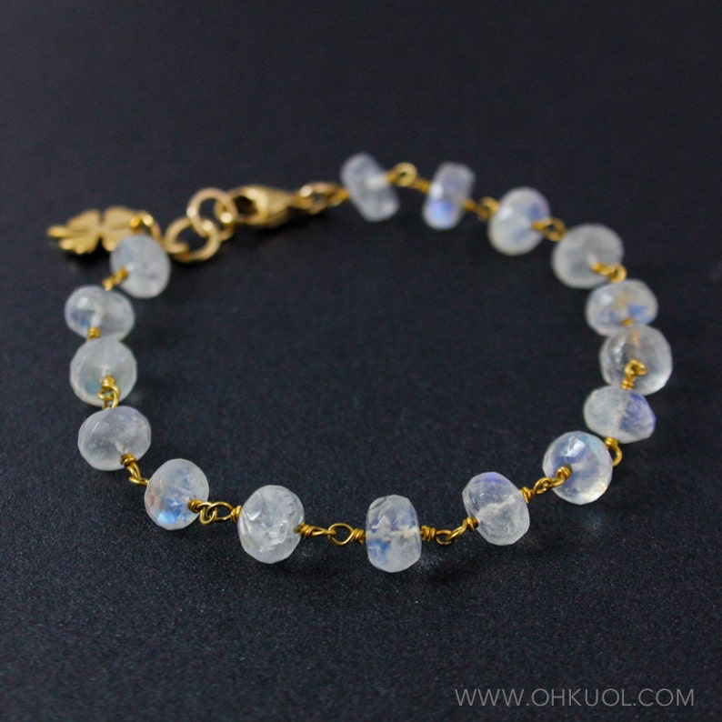 May include: A delicate gold chain bracelet with a small leaf charm and white moonstone beads.