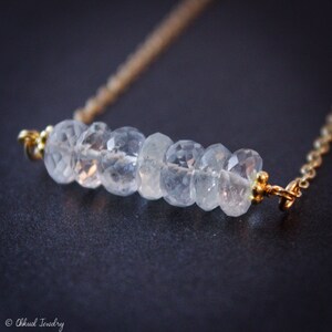 May include: A delicate gold chain necklace with a bar of clear faceted aquamarine stones.