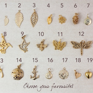 May include: A set of 19 gold-toned metal charms, each with a different design, including a hummingbird, a dragonfly, a butterfly, a leaf, a pine cone, a seashell, an anchor, a heart, and a wishbone. The charms are numbered 1 through 19.
