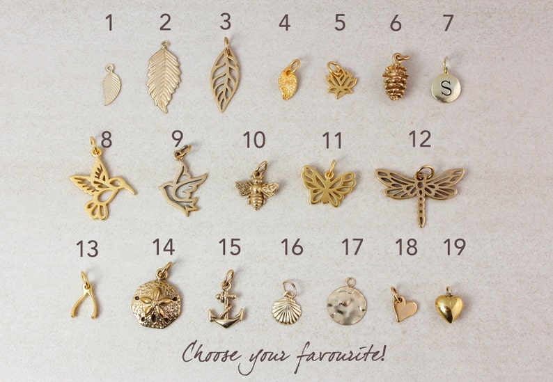May include: A set of 19 gold-toned metal charms, each with a different design, including a hummingbird, a dragonfly, a butterfly, a leaf, a pine cone, a seashell, an anchor, a heart, and a wishbone. The charms are numbered 1 through 19.
