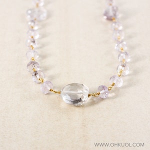 May include: A delicate necklace made with faceted amethyst beads and a large clear quartz pendant. The necklace is strung on gold wire.