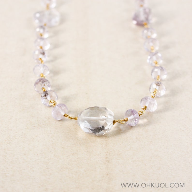 May include: A delicate necklace made with faceted amethyst beads and a large clear quartz pendant. The necklace is strung on gold wire.