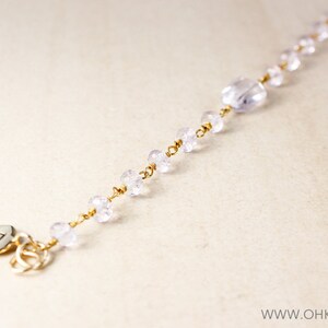 May include: A delicate gold chain bracelet with clear crystal beads and a silver charm with the letter 'B'.