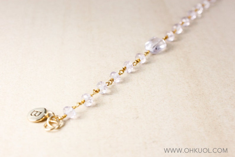 May include: A delicate gold chain bracelet with clear crystal beads and a silver charm with the letter 'B'.
