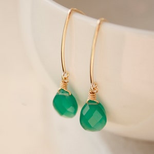 May include: A pair of gold earrings with green gemstone drops. The earrings are made with delicate wire wrapping and have a simple, elegant design.