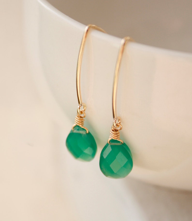 May include: A pair of gold earrings with green gemstone drops. The earrings are made with delicate wire wrapping and have a simple, elegant design.