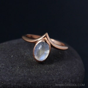 Puede incluir: Un anillo de oro rosa con un dise&ntilde;o delicado y puntiagudo y una piedra ovalada de piedra lunar.